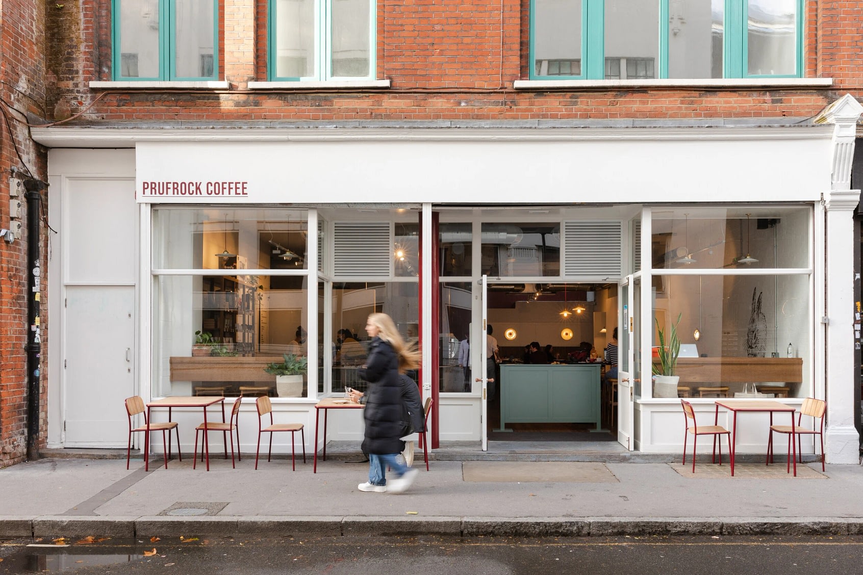 A woman with blonde hair walks passed Prurock Coffee on Leather Lane