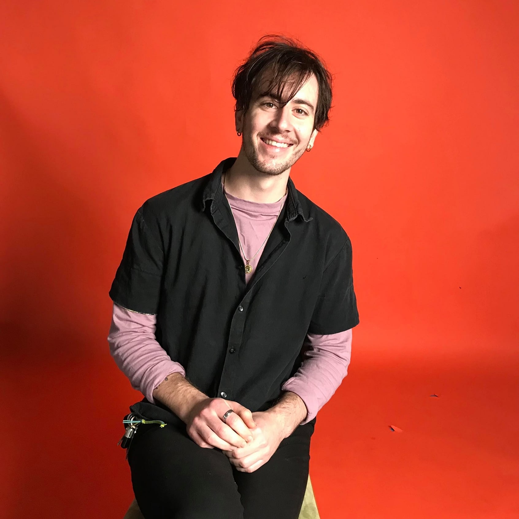 James Gatling sitting down with orange background